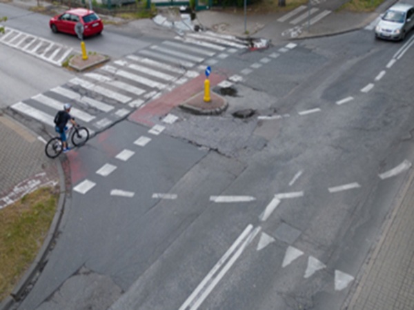 Rowerzysta na uszkodzonym skrzyżowaniu miejskim z przejściem dla pieszych