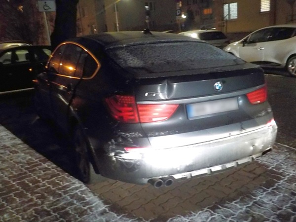 Widok z tyłu uszkodzonego ciemnoszarego BMW serii 5 Gran Turismo ze szronem na powierzchni.