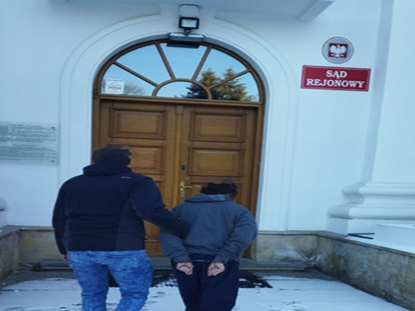 Dwóch mężczyzn eskortowanych przed polskim Sądem Rejonowym. Widoczny znak „Sąd Rejonowy”.