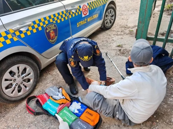 Policjanci miejscy udzielają pierwszej pomocy osobie rannej.