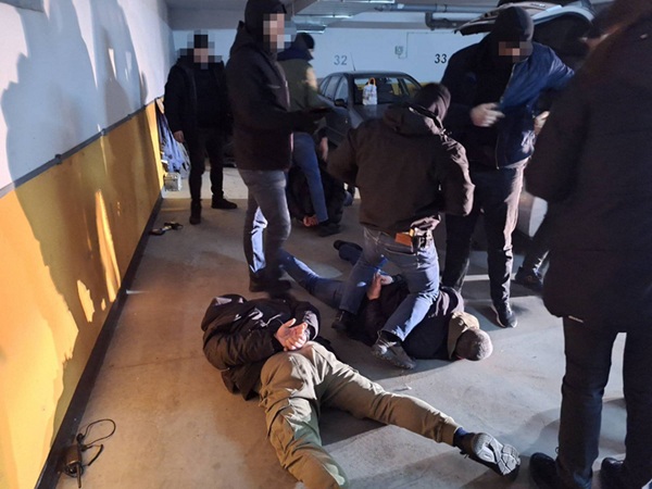 Policjanci zatrzymują podejrzanych na parkingu.