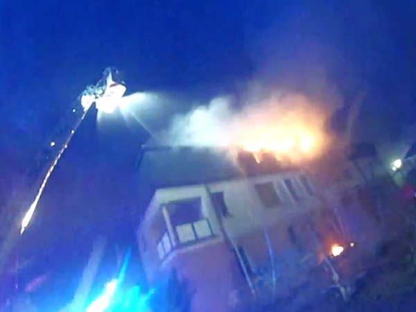 Strażacy gaszą pożar domu w nocy za pomocą wozu drabinowego