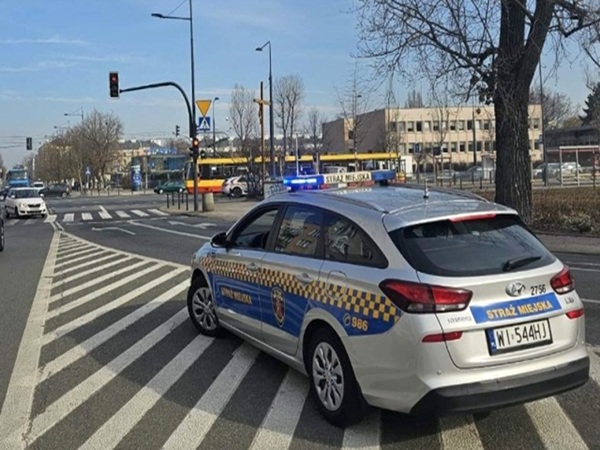Srebrny radiowóz Hyundai i30, Straż Miejska, tablica rejestracyjna NI 544HJ, na skrzyżowaniu.