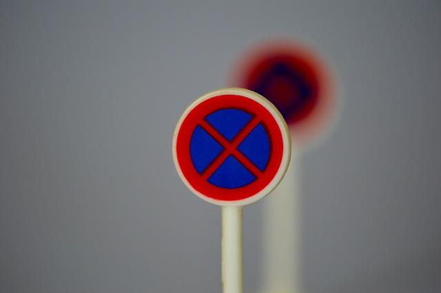 Zbliżenie znaku zakazu parkowania z niebieskim okręgiem i czerwonym X.