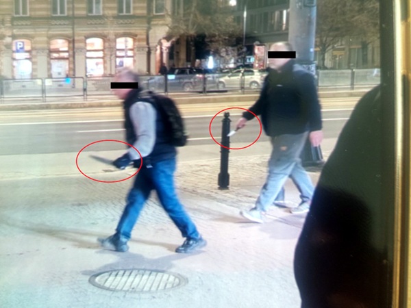 Dwóch mężczyzn spacerujących nocą, jeden z nożem. Możliwy napad lub sprzeczka.