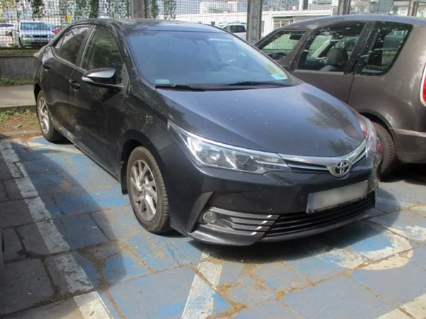 Ciemnoszara Toyota Corolla zaparkowana na miejscu parkingowym.