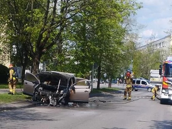 Spalony samochód po pożarze, strażacy na miejscu.