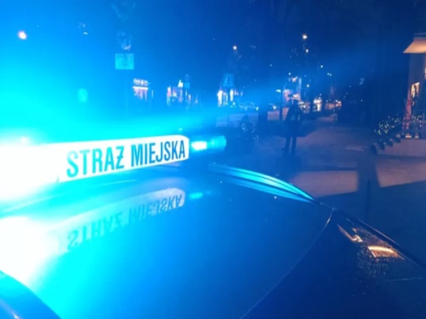 Radiowóz Straży Miejskiej z migającymi w nocy niebieskimi światłami