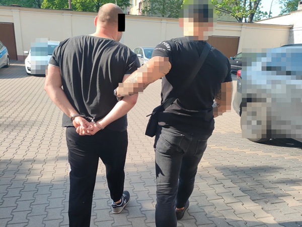 Policjant aresztujący podejrzanego, widoczne kajdanki.