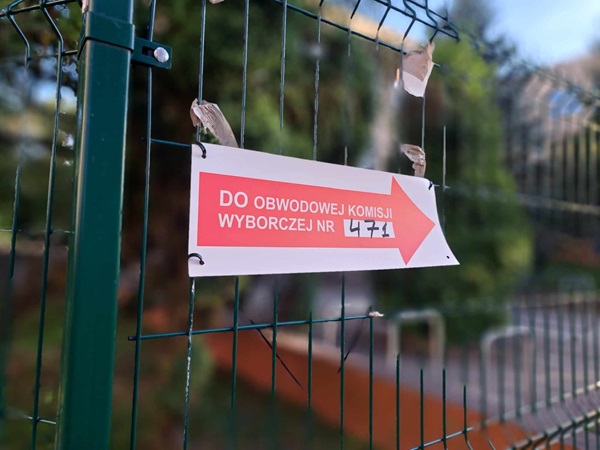 Znak na ogrodzeniu kieruje wyborców do lokalu wyborczego nr 471