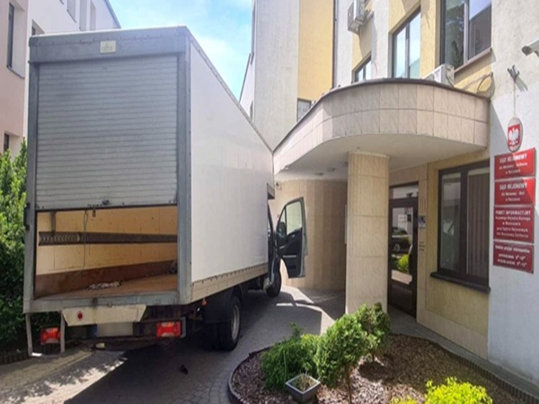 Samochód dostawczy zaparkowany nielegalnie w pobliżu sądu. Tylna klapa samochodu dostawczego jest otwarta.