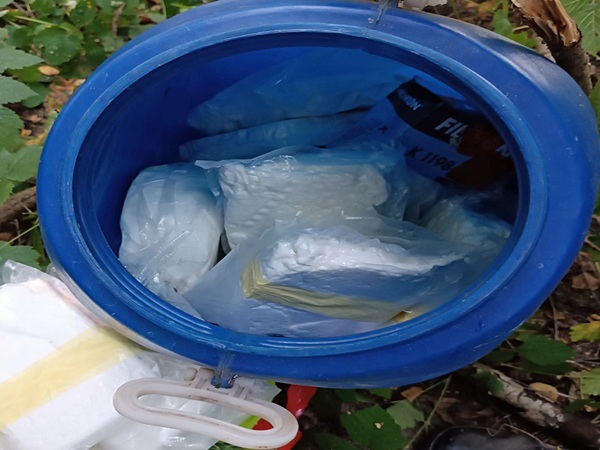 Niebieski pojemnik wypełniony białymi paczkami z proszkiem, prawdopodobnie narkotykami. Dowód na zatrzymanie narkotyków.