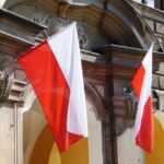 Dwie polskie flagi wiszą na ozdobnej fasadzie budynku