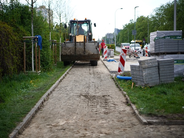 Robotnik budowlany używa spychacza do układania nowego chodnika.