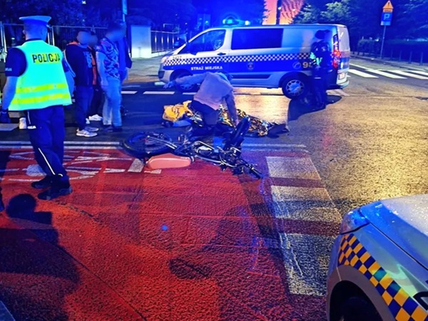 Miejsce wypadku: ranny rowerzysta na ziemi w pobliżu radiowozu i furgonetki. Uderzenie i ucieczka.