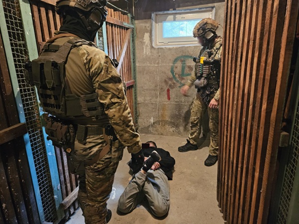 Funkcjonariusze taktyczni zatrzymują podejrzanego w zamkniętej przestrzeni.