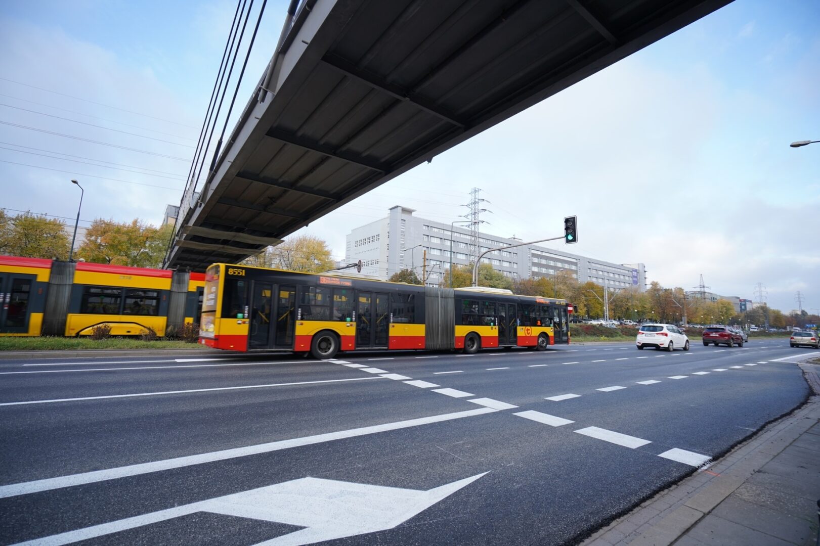 Autobus i tramwaj na skrzyżowaniu Mokotów, na zdjęciu nowa ścieżka rowerowa zamiast kładki dla pieszych.