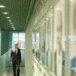 Biznesmen idący korytarzem w nowoczesnym budynku biurowym.