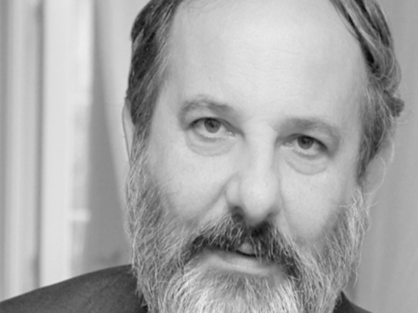 Czarno-białe zdjęcie mężczyzny z brodą i zamyślonym wyrazem twarzy.