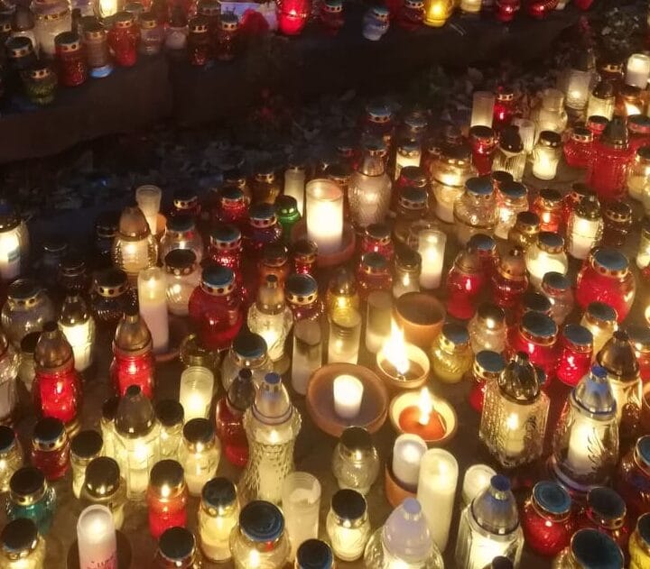 Liczne zapalone świece i lampy wotywne na cmentarzu, upamiętniające Dzień Wszystkich Świętych.