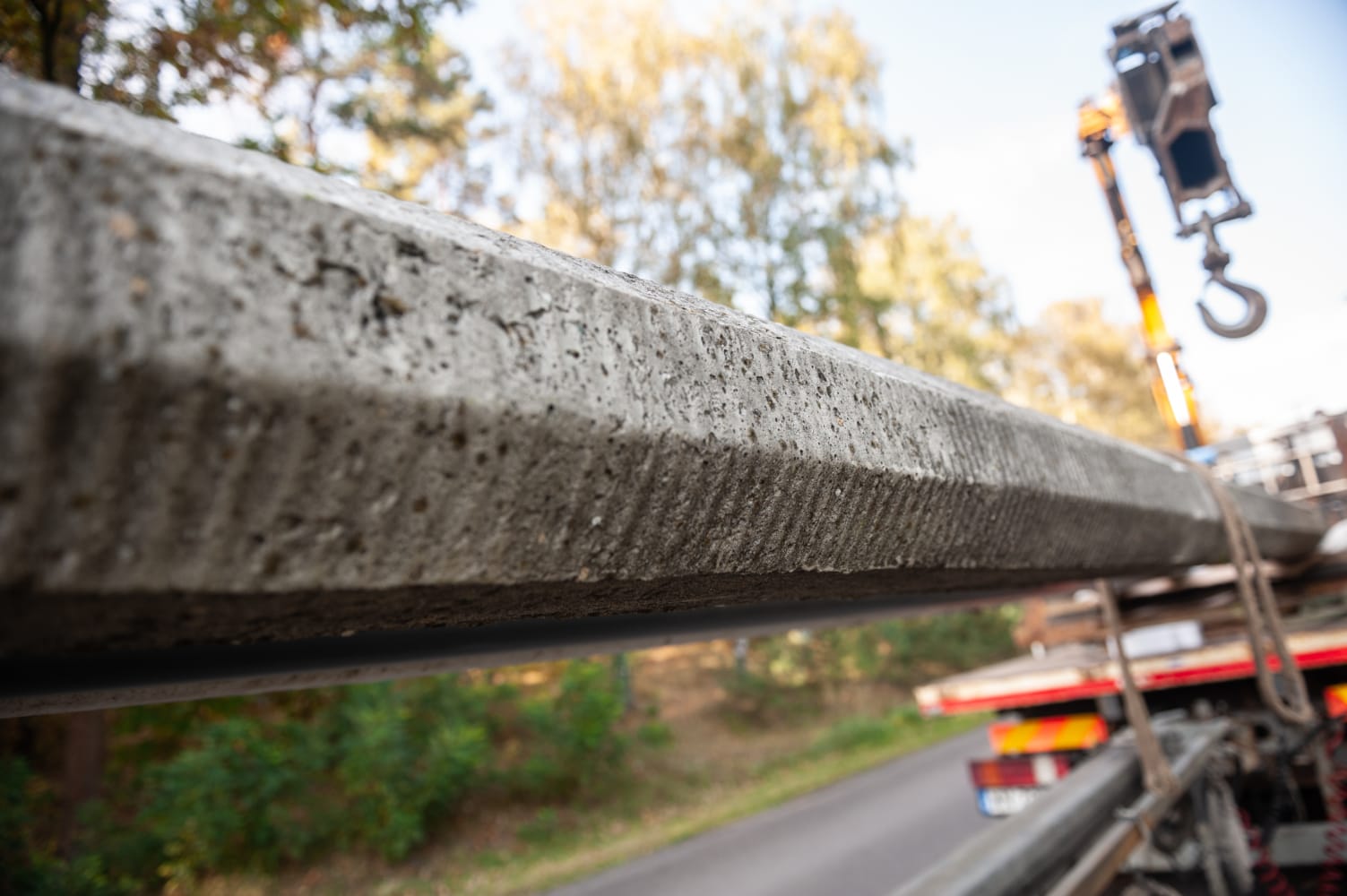 Zbliżenie na belkę betonową podnoszoną przez dźwig.