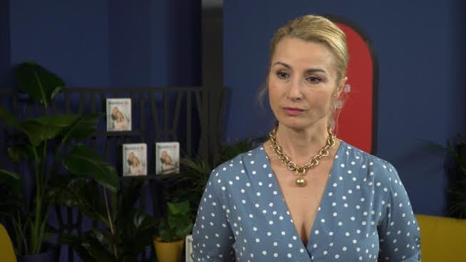 Kobieta w niebieskiej sukience w kropki, złoty naszyjnik