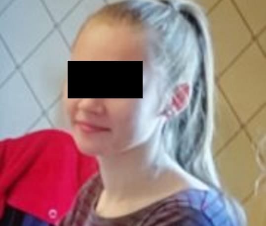 Nastolatka z blond włosami związanymi w kucyk i zasłoniętymi oczami.