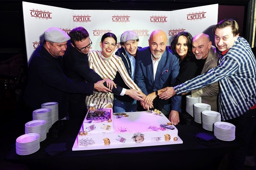 Aktorzy z Teatru Capitol Club świętują przy tortu w kształcie pieniędzy.