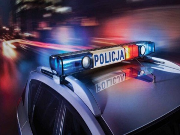 Samochód policyjny z migającymi światłami; na pasku świetlnym widoczny napis „POLICJA”.