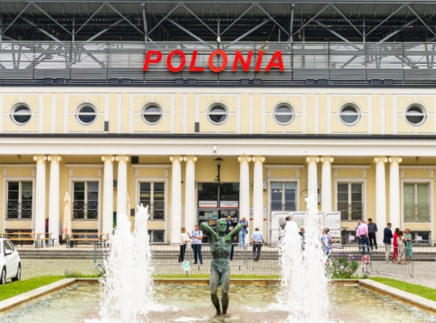 Stadion Polonii Warszawa z zewnątrz z fontanną i pomnikiem