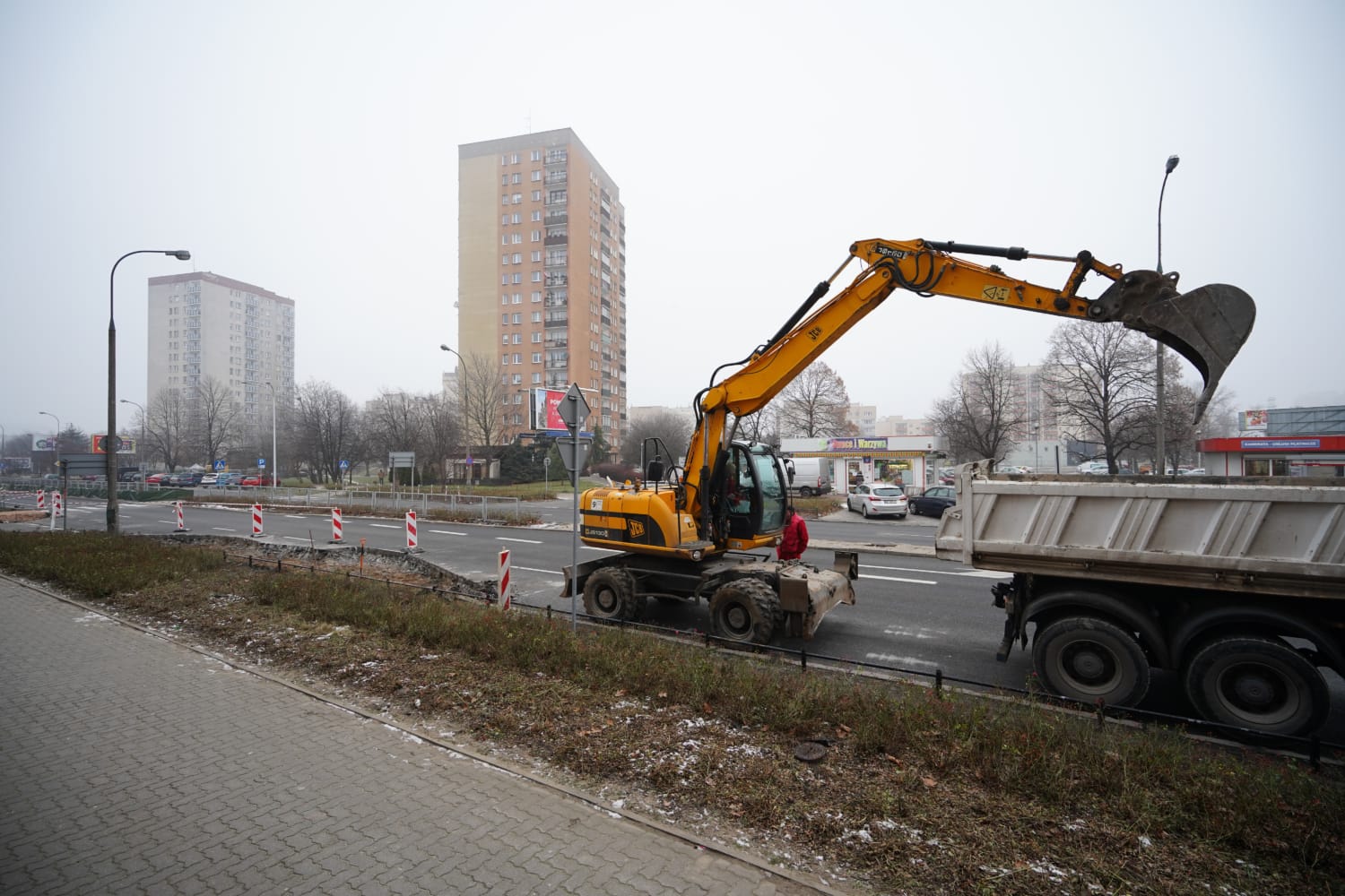Żółta koparka ładująca wywrotkę podczas budowy drogi