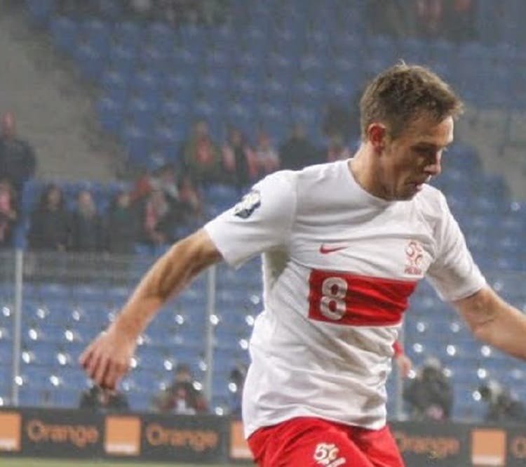 Piłkarz ubrany w koszulkę z numerem 8 dryblujący piłkę