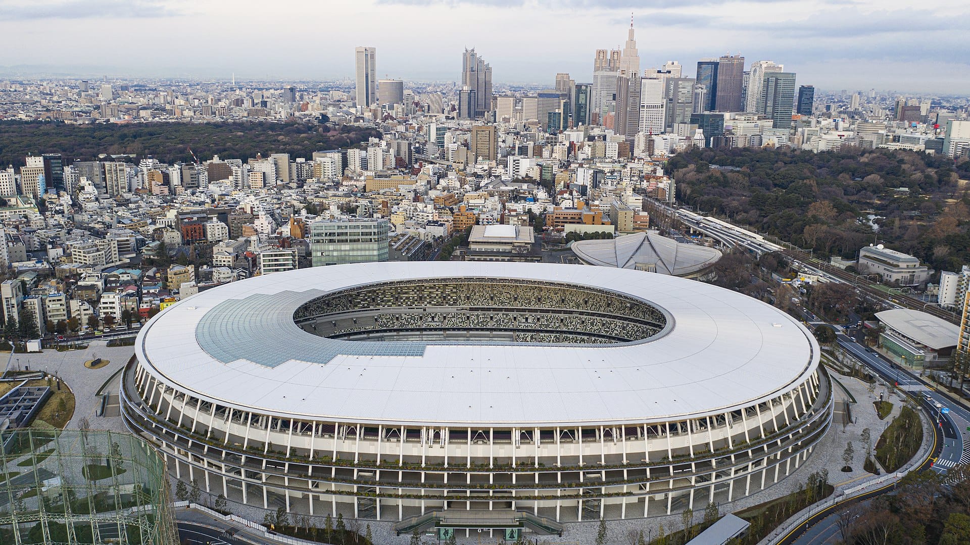 Widok z lotu ptaka na Stadion Olimpijski w Tokio w Japonii, prezentujący jego nowoczesny design na tle panoramy miasta.