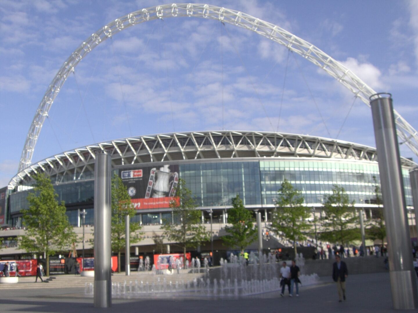 Charakterystyczny łuk i fasada stadionu Wembley z dużą reklamą.