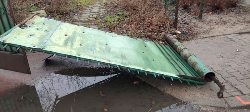 Uszkodzony zielony metalowy przenośnik taśmowy rolniczy leżący na ziemi