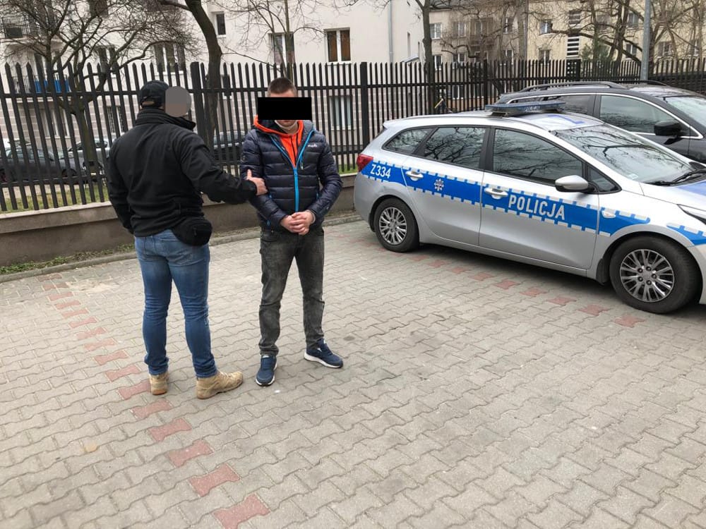 Policjant aresztujący podejrzanego w pobliżu radiowozu. POLICJA