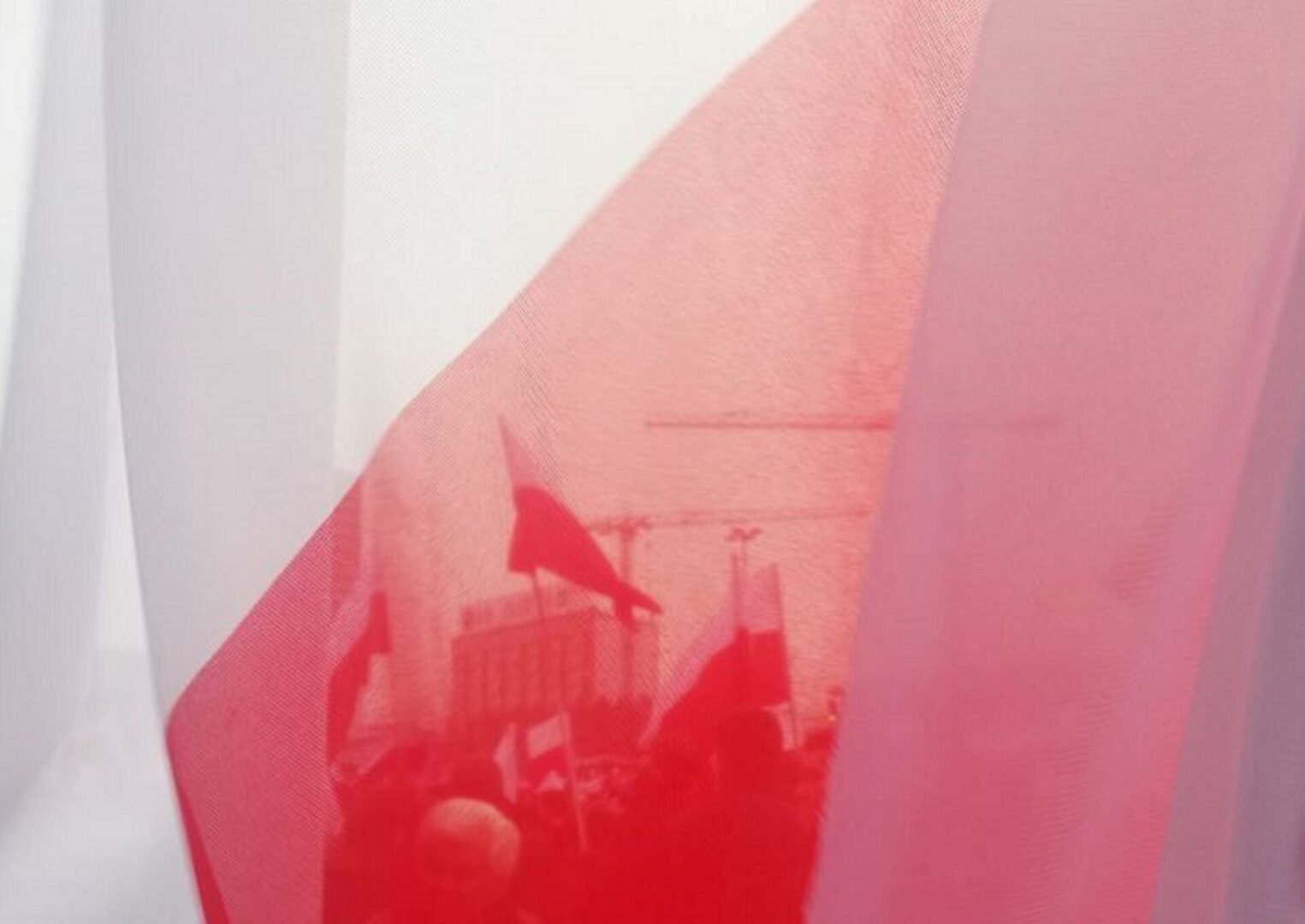 Prześwitująca, czerwono-biała tkanina odsłaniająca polskie flagi i protestujących.