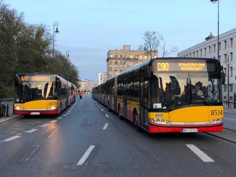 Dwa autobusy miejskie w Warszawie, numery 8878 i 8534, na ulicy miejskiej. Wyświetlono trasę C90.