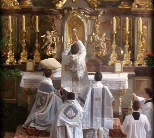 Katolicki ksiądz odprawiający mszę, podnoszący Eucharystię