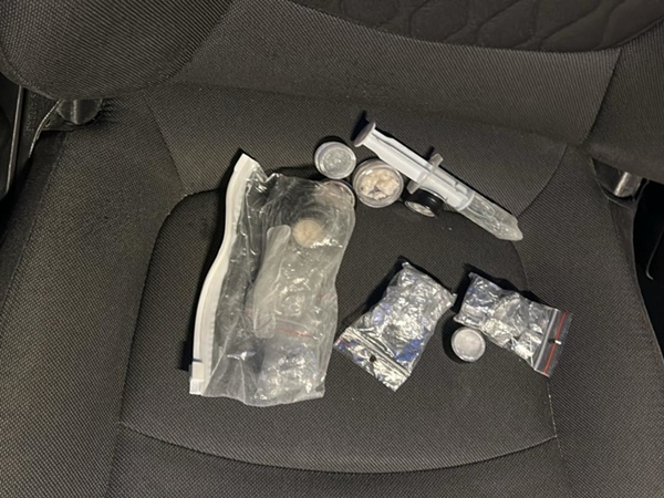 Dowody obecności narkotyków w pojeździe: torby z narkotykami, strzykawka i małe pojemniki.