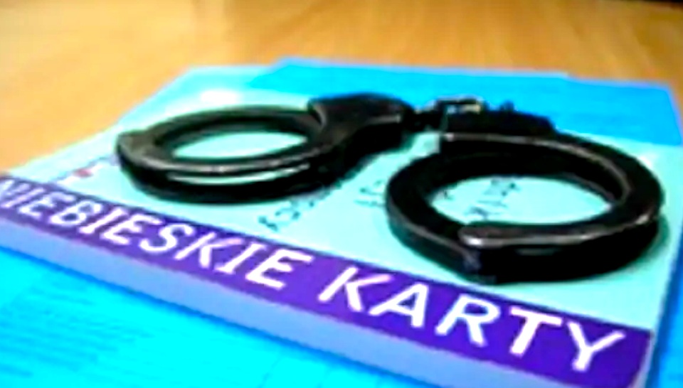 Kajdanki na niebieskim dokumencie z polskim tekstem "Niebieskie Karty".