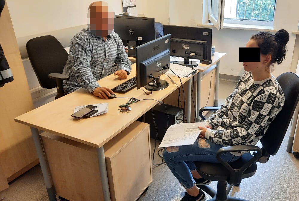 Mężczyzna i kobieta siedzą przy biurku w biurze, przeglądając dokumenty. Stoją naprzeciwko siebie, zaangażowani w rozmowę.