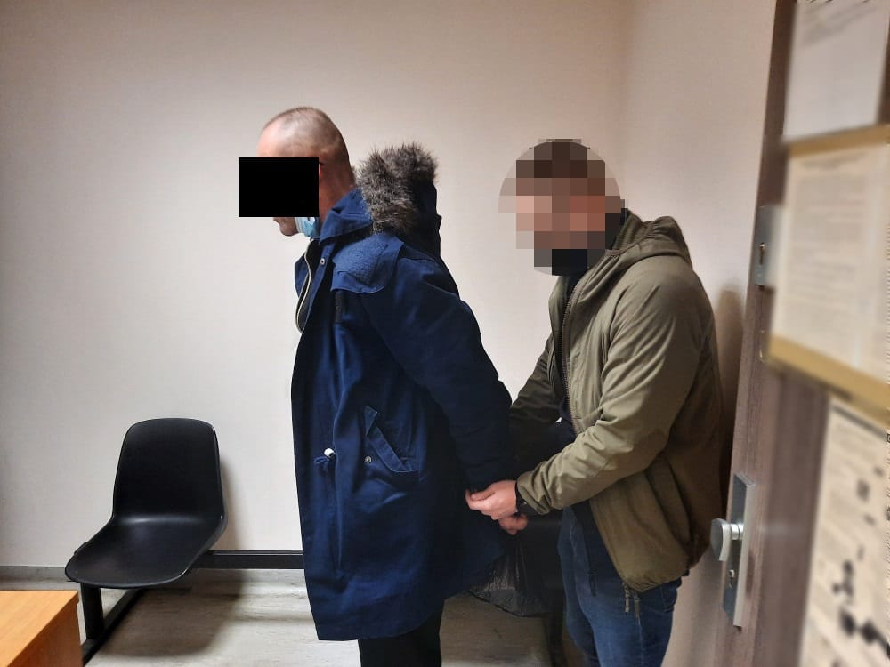 Policjant aresztujący podejrzanego w kajdankach.