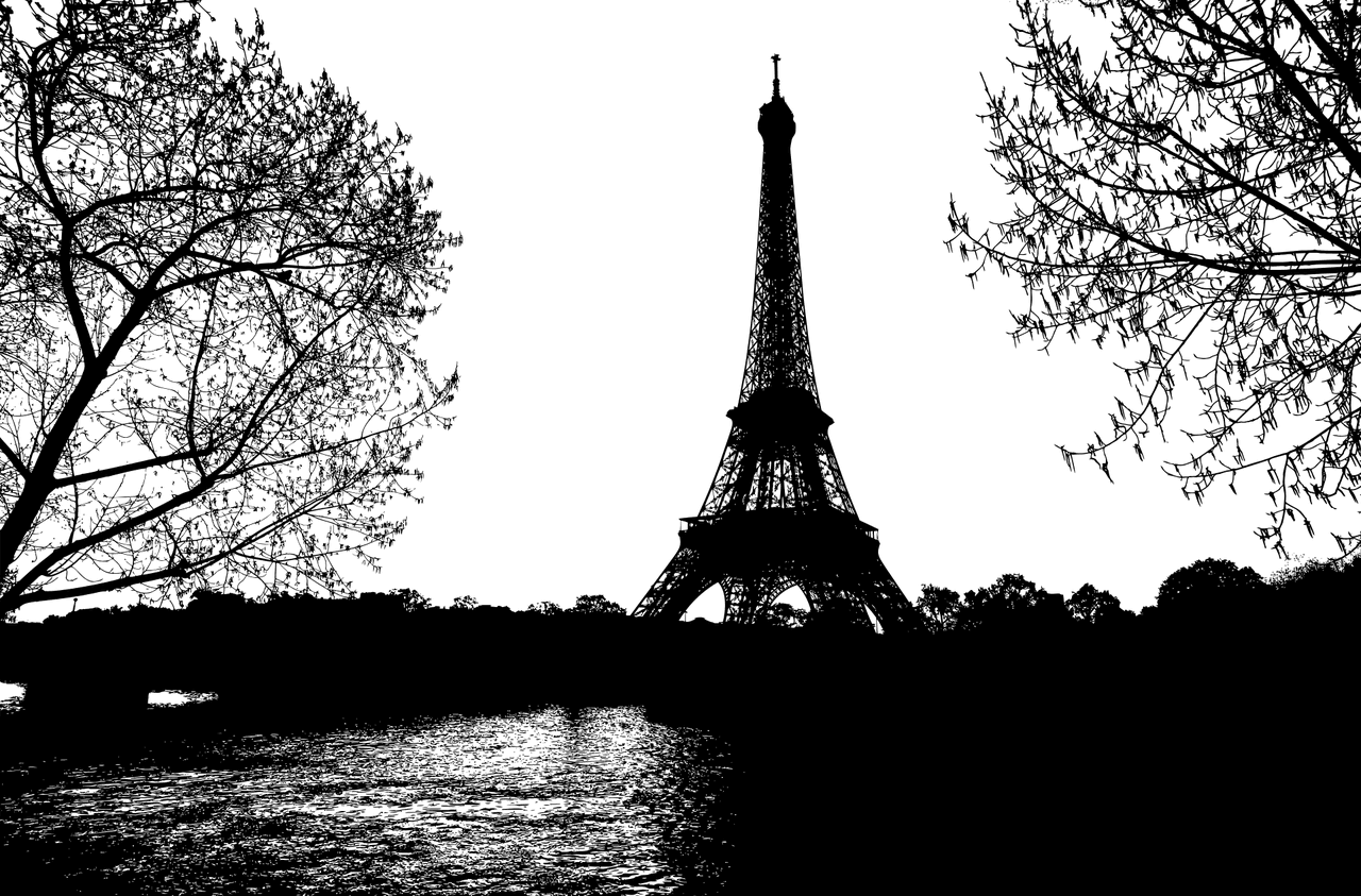 Sylwetka Wieży Eiffla o zmierzchu, w otoczeniu drzew.