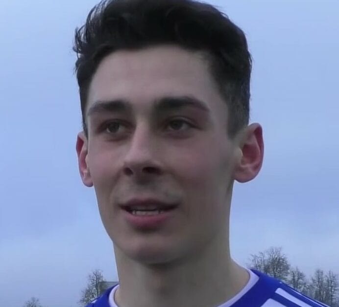 Młody mężczyzna z krótkimi, ciemnymi włosami, uśmiechający się do kamery.