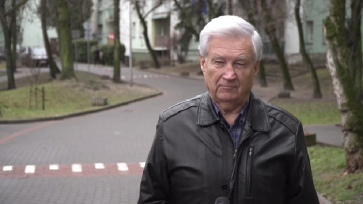 Starszy mężczyzna w czarnej skórzanej kurtce przemawia na zewnątrz