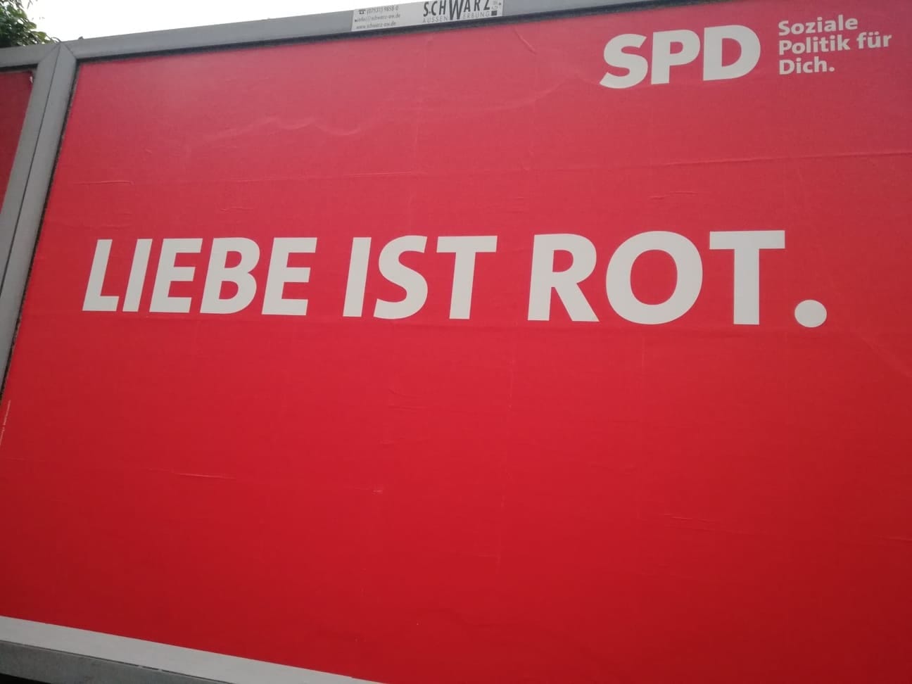 Duży czerwony billboard z napisem „LIEBE IST ROT” (Miłość jest czerwona) w kolorze białym; powyżej logo SPD.