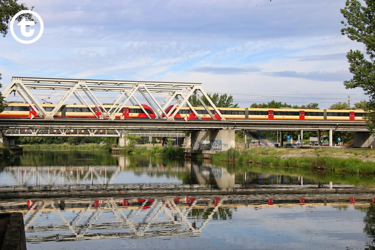 Czerwony i żółty pociąg przejeżdżający przez most nad kanałem