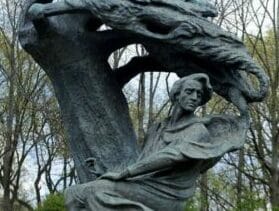 Brązowa statua kobiety siedzącej pod stylizowanym drzewem