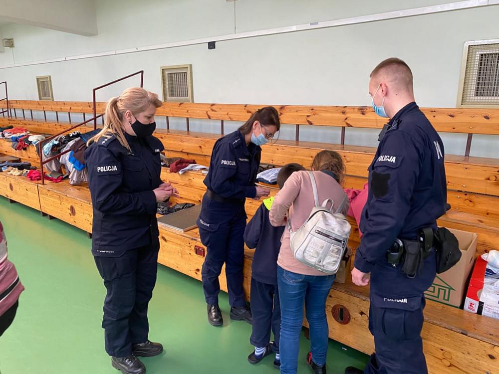 Polscy policjanci pomagają dzieciom w przekazywaniu odzieży.